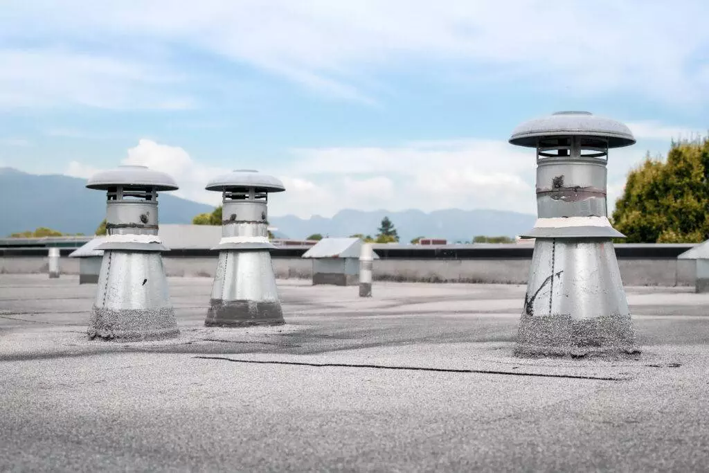Flat roof vents on building with 2-ply SBS or modified bitumen roofing system.